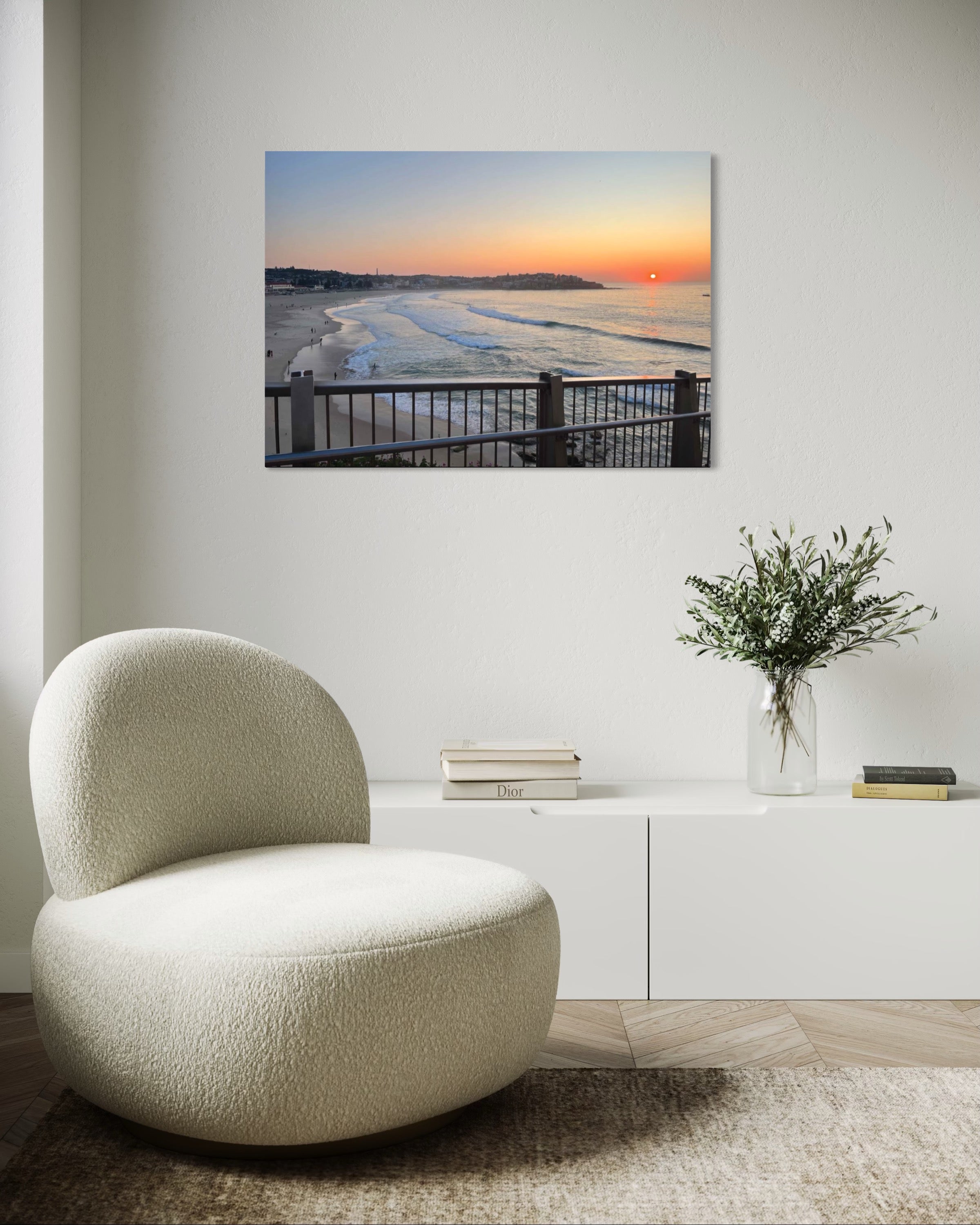 Modern living room with a textured chair, vase with flowers, and wall art of a sunset over water.