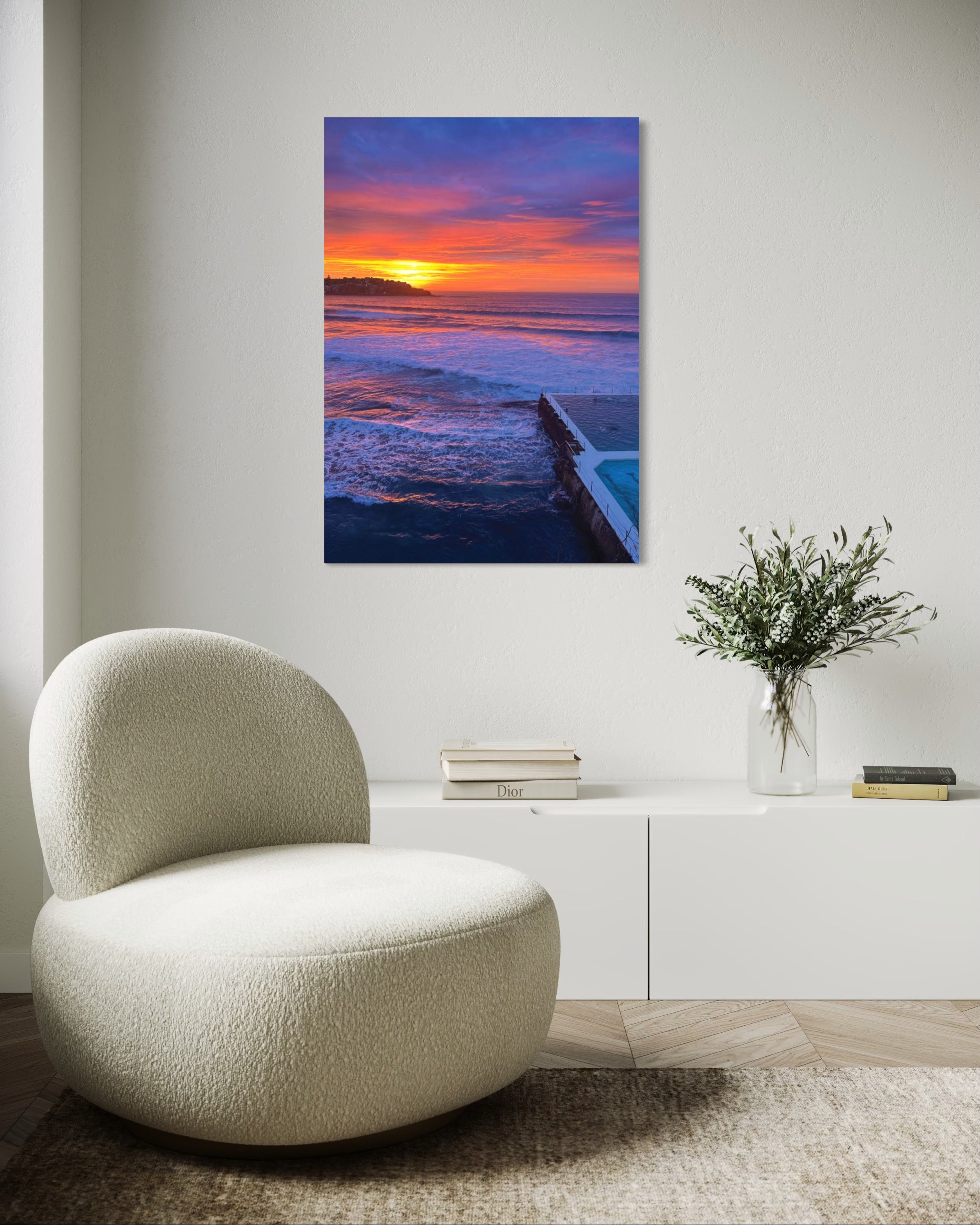 Modern chair in a room with a sunset over water painting on the wall.