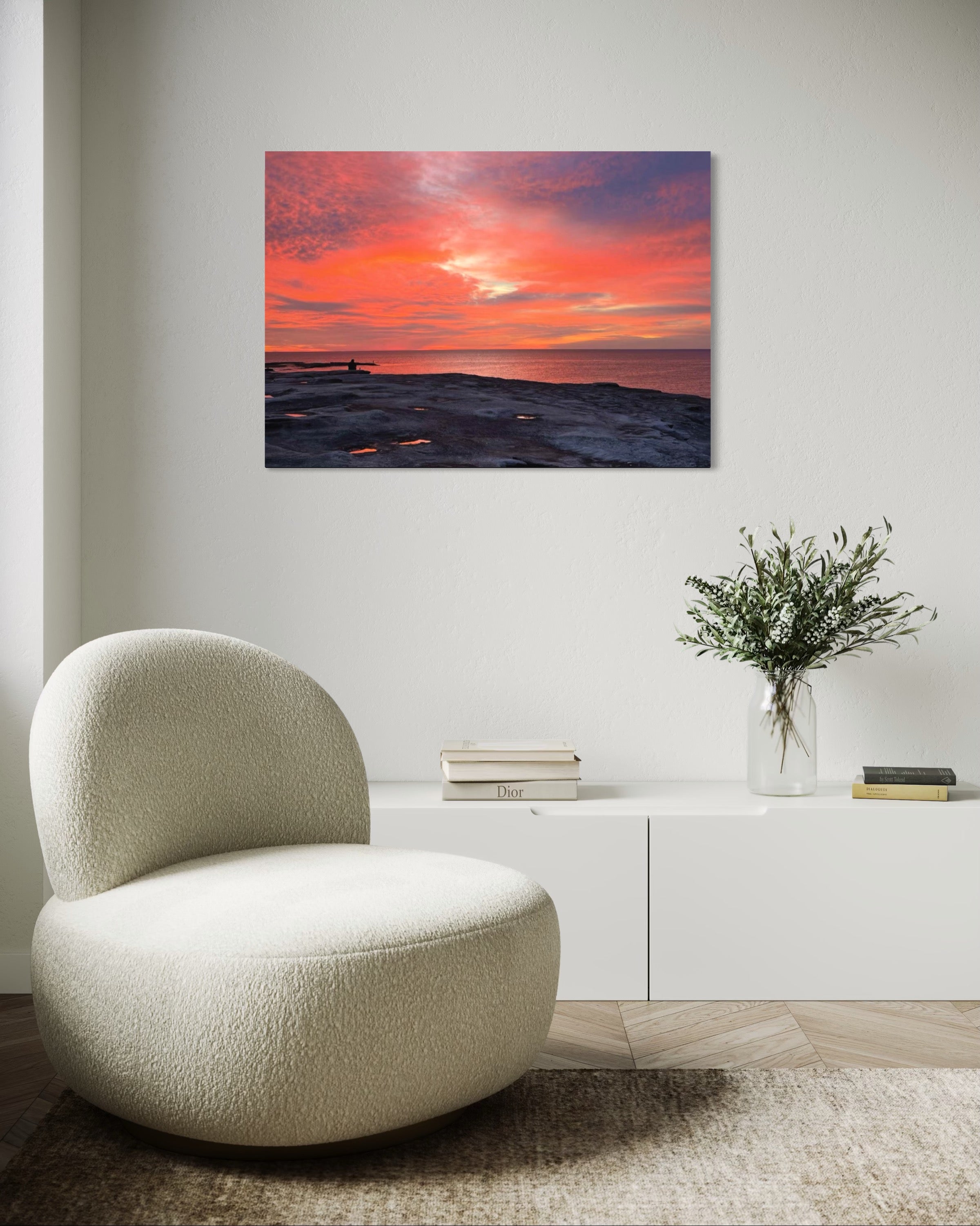 Modern living room with a textured chair, vase with flowers, and sunset painting on the wall.