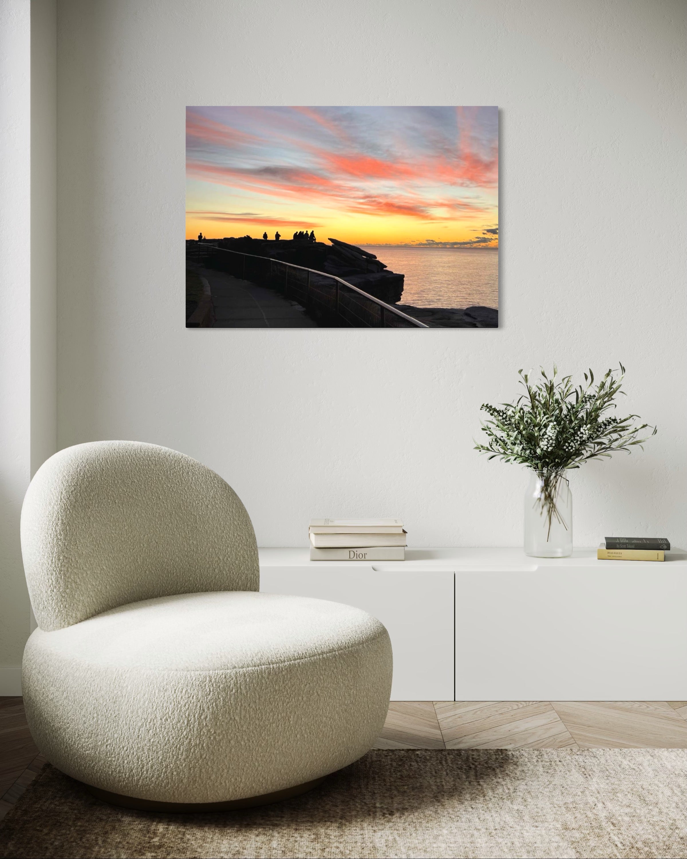 Modern interior with a textured chair, vase with flowers, and sunset painting on the wall.