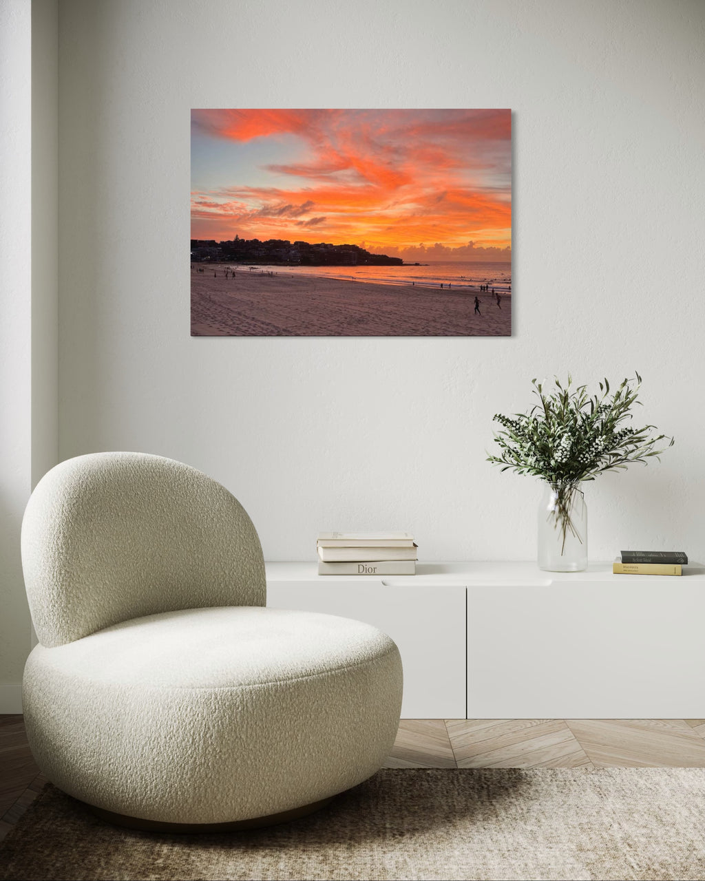 Modern living room with a textured chair, vase with flowers, and sunset beach scene painting.