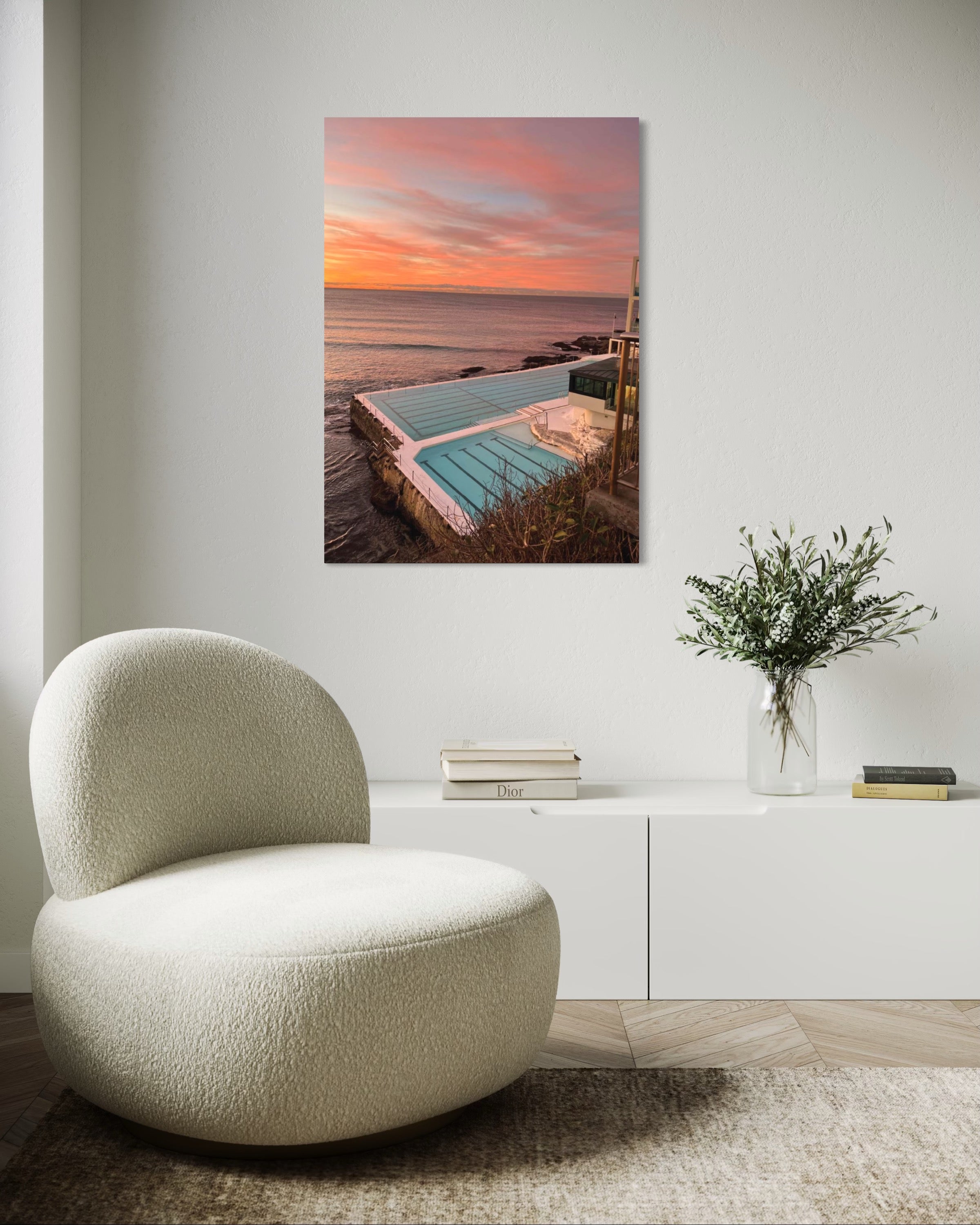 Modern chair in a room with a large wall art of a pool at sunset.