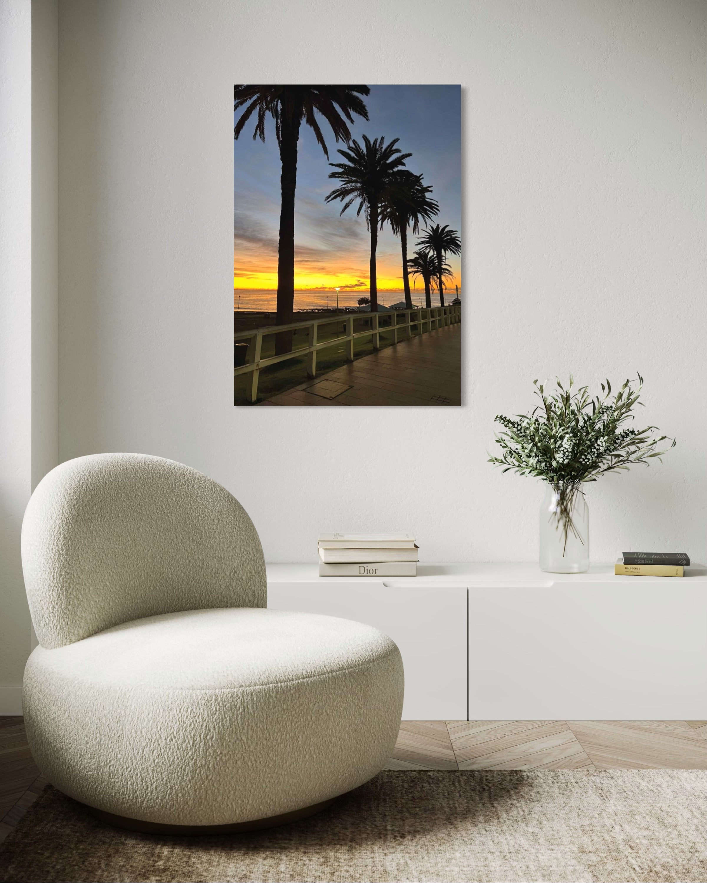 Modern chair in a room with a decorative wall piece of palm trees and sunset.