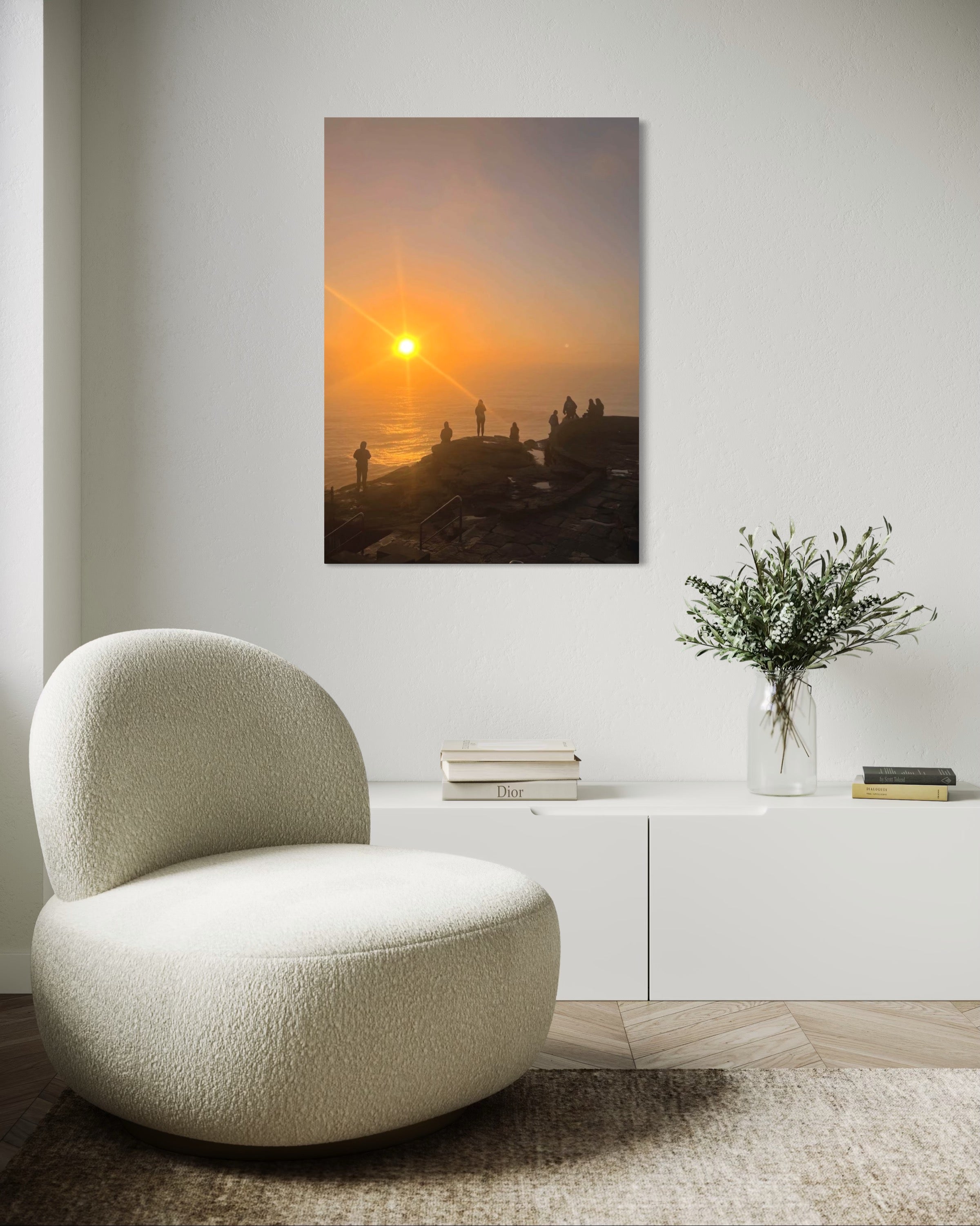 Modern living room with a textured chair, vase with flowers, and wall art of a sunset.