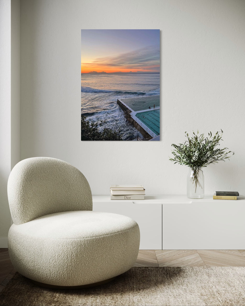 Modern interior with a textured chair, vase with flowers, and a large wall art of a sunset over water.