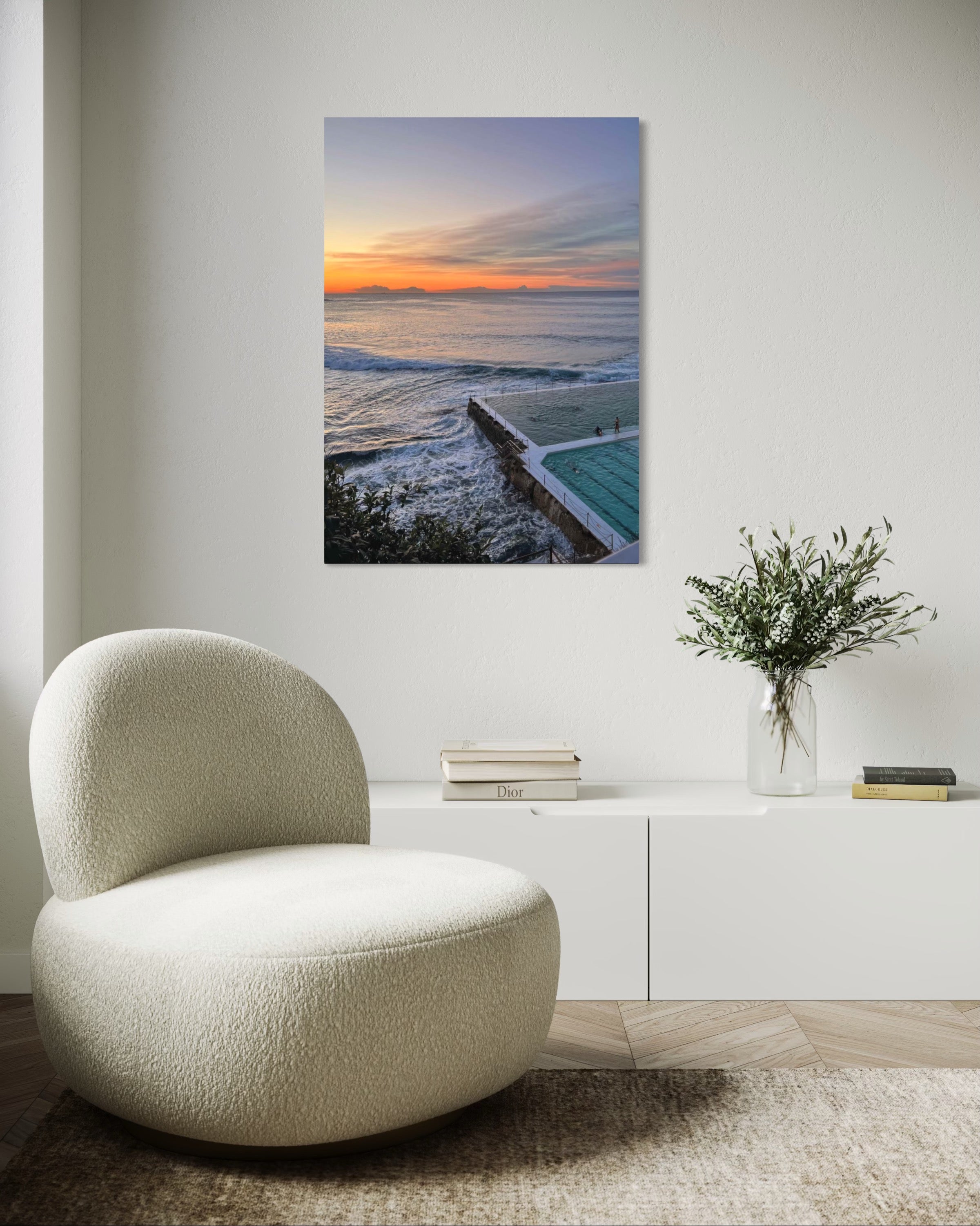 Modern interior with a textured chair, vase with flowers, and a large wall art of a sunset over water.